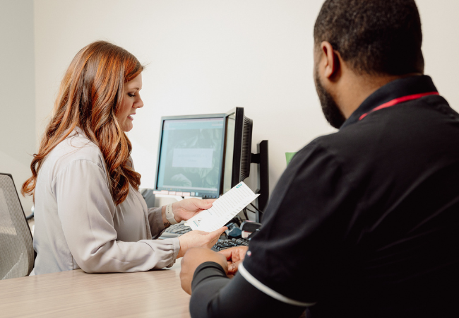 Image of GBT banker helping a customer with a their bank account.