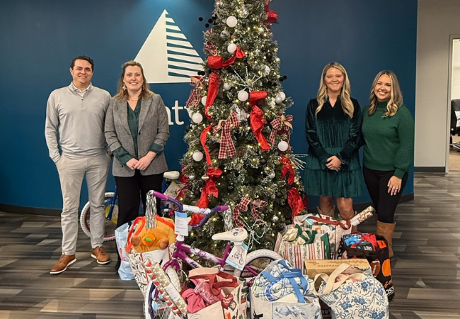 Image of GBT employees standing around a Christmas tree with presents at the bottom