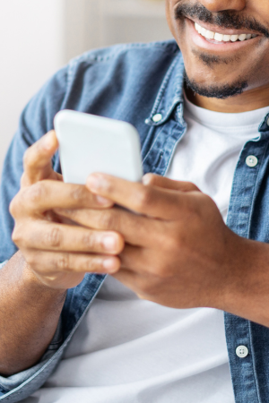 Man smiling and holding his mobile phone in both hands.