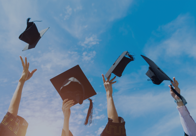 four graduation caps thrown into the sky.