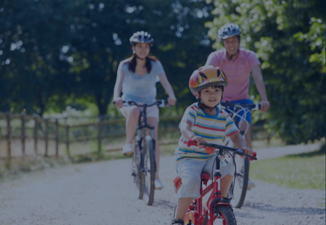 A mom and dad riding their bikes with their young son.